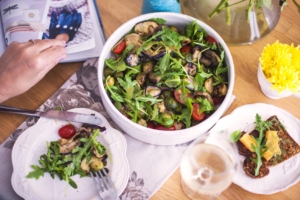 a bowl of ethiopian vegetables surrounded by smaller plates and water glasses with someone dishing up
