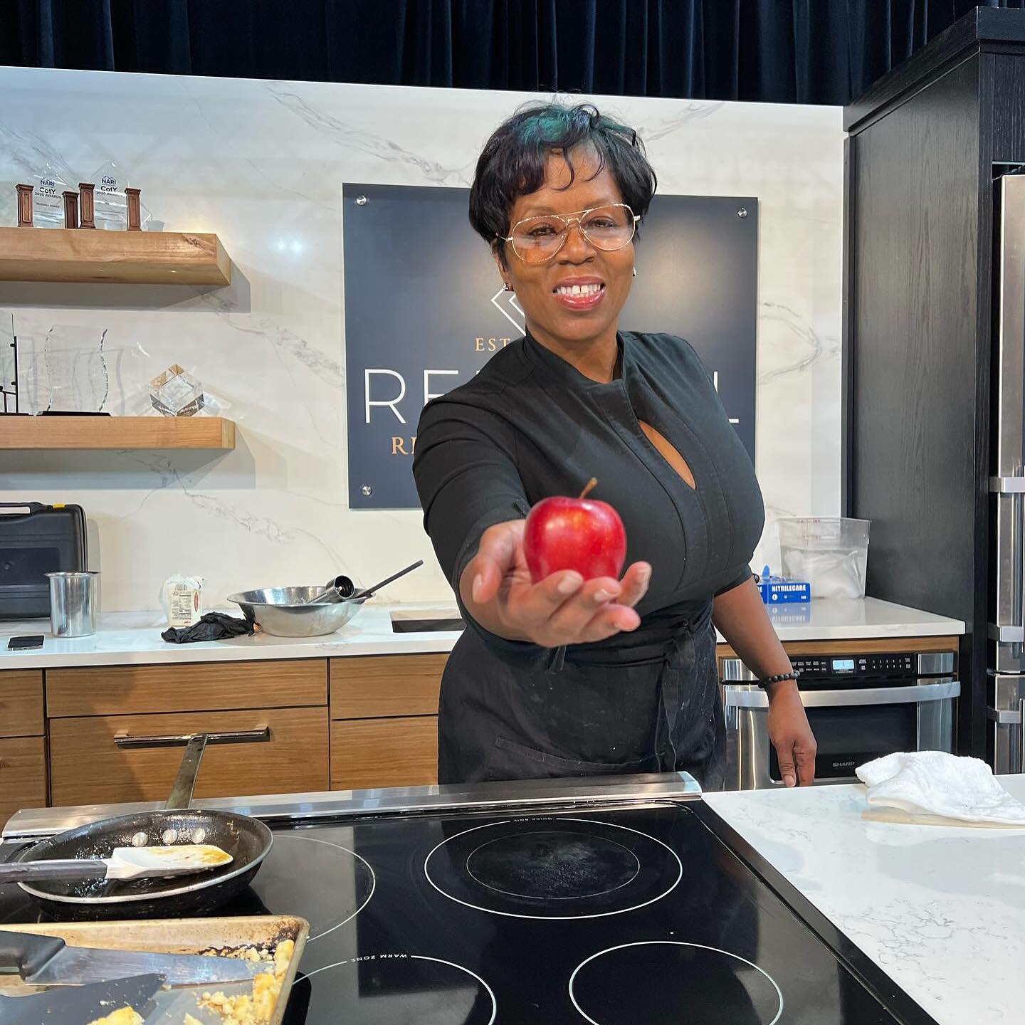 Lizzie Lou's Too Cafe owner Nessa Victorian in a kitchen holding out an apple