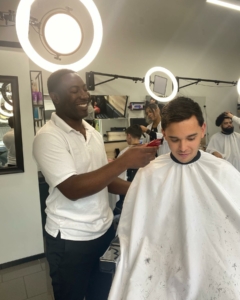 Rain City Barbershop owner Percy cutting a clients hair