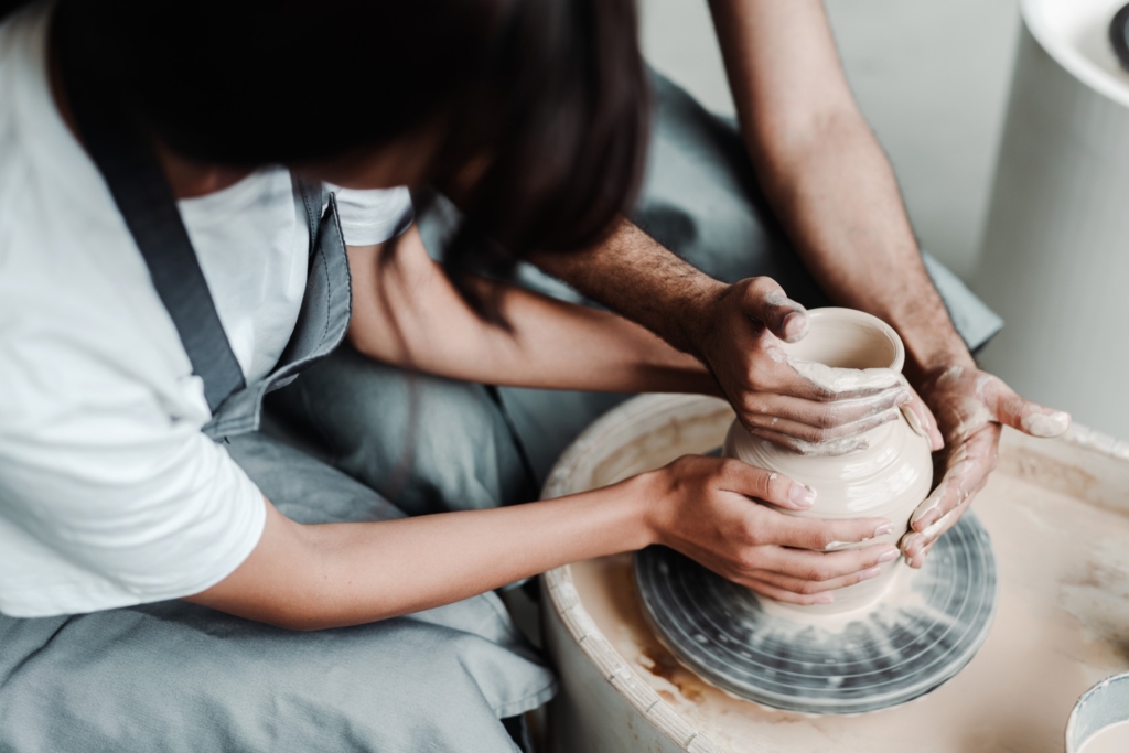 Modeling a pot on a potter's wheel. Male and female hands close up. A date in a hobby workshop. High quality photo